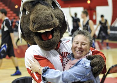 Lorna Larsen hugs the SAIT Trojans basket ball mascot in Calgary - 2014