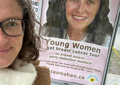 Amy standing by one of her campaign signs at a bus stop in Peterborough