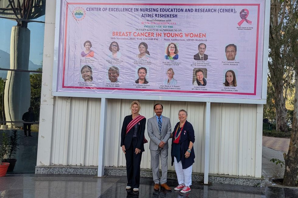 Lorna in front of the sign outside the AIMMS Breast Cancer in Young Women Nursing Symposium